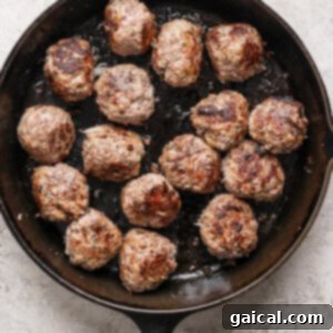 A cast-iron skillet contains 16 evenly browned meatballs, signifying they are ready to be removed and the sauce preparation to begin.