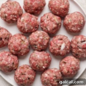 A plate filled with raw, evenly-sized Minnesota Swedish Meatballs, meticulously arranged in a circular pattern on a clean white surface, ready for cooking.