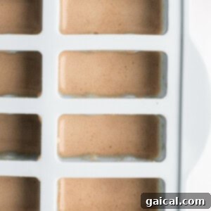 Ice tray filled with light brown liquid, viewed from the top.