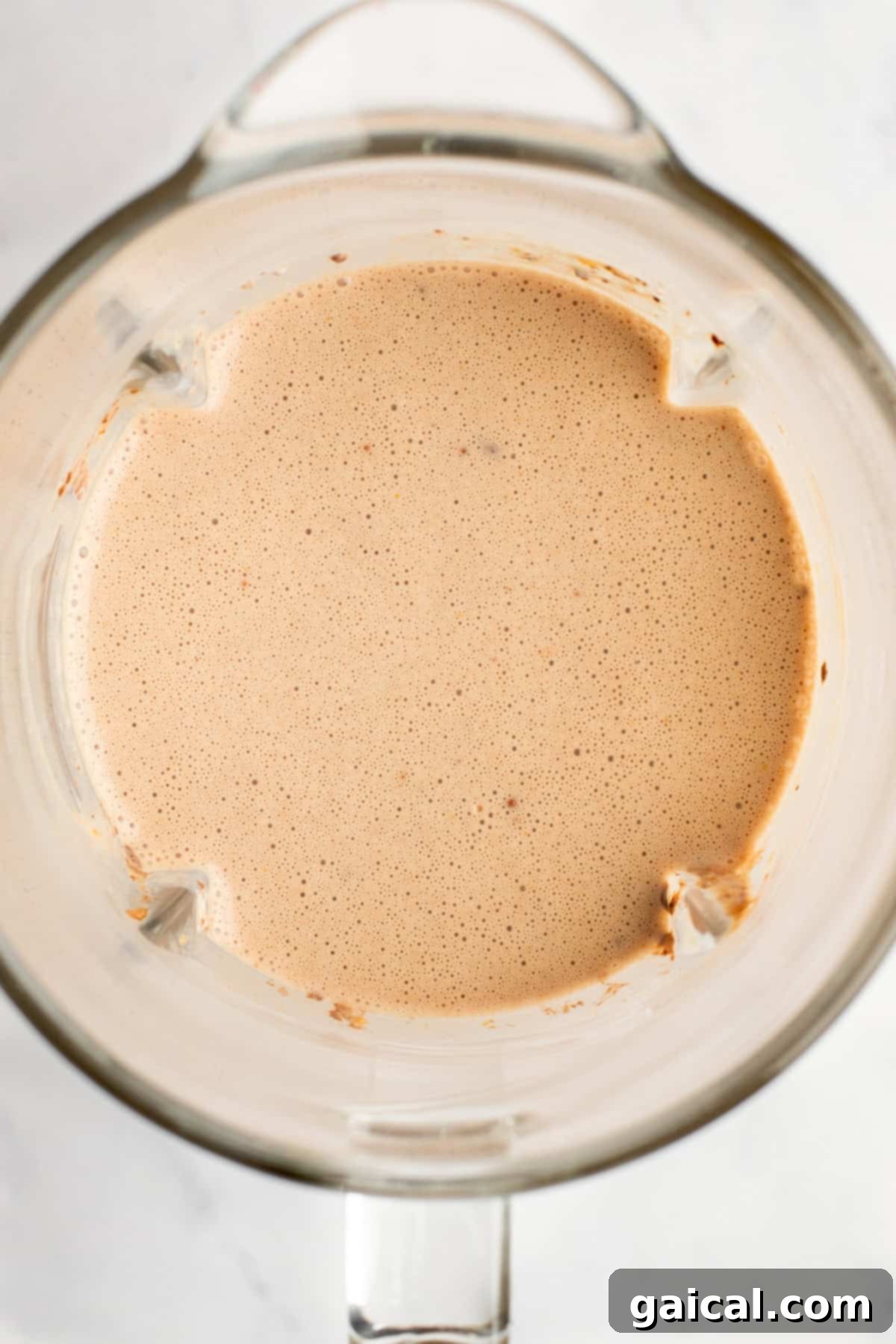 Guilt-Free Protein Fudge Pops 6 A top view of a blender containing a smooth, light brown liquid mixture.