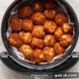 Golden brown breaded balls are meticulously arranged in a circular pattern within an air fryer basket, ready for baking.