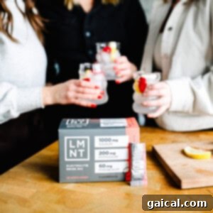 Nighttime Nectar 4 Three friends enjoying drinks, including a refreshing sleepy girl mocktail, sit beside a box of LMNT electrolyte drink mix on the wooden table.