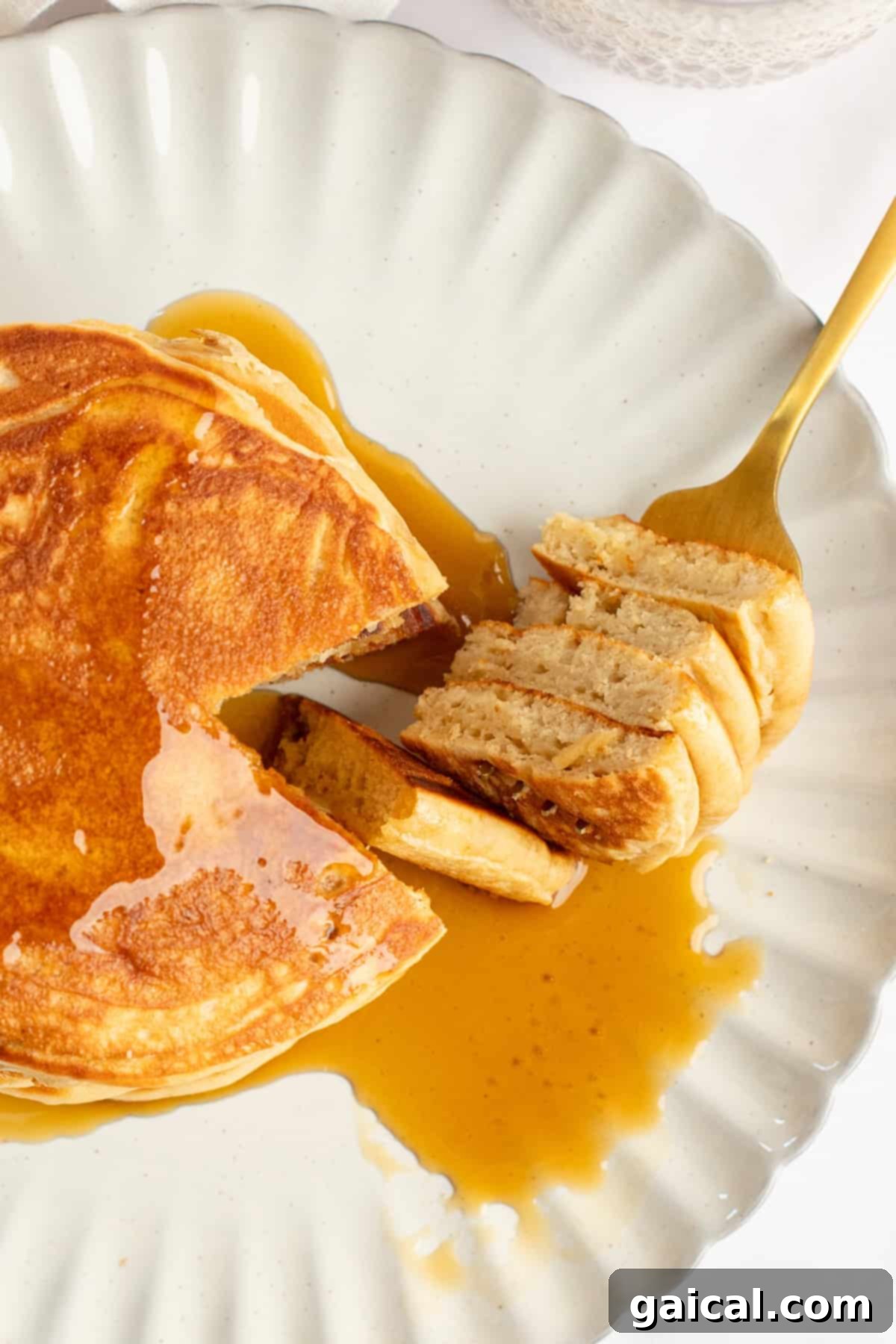 Power-Packed Pancakes 5 A close-up shot of a plate of pancakes, partially eaten, with rich maple syrup drizzled over them. A fork holds a perfectly cut portion of the pancakes, ready to be enjoyed.