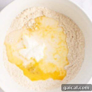 Power-Packed Pancakes 7 A white bowl containing flour with a well in the center holding cracked eggs and yogurt.