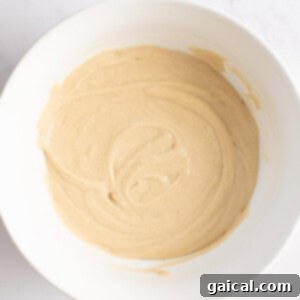 Power-Packed Pancakes 8 A white bowl containing smooth, light brown batter on a light surface.