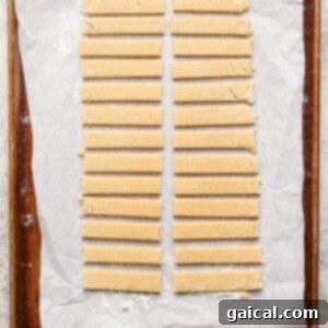 Protein-Packed Peanut Butter Twix Bars 8 Strips of dough neatly arranged on a parchment-lined baking sheet.