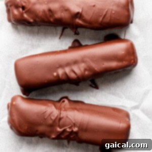 Protein-Packed Peanut Butter Twix Bars 12 Five chocolate-coated bars arranged in a row on parchment paper.