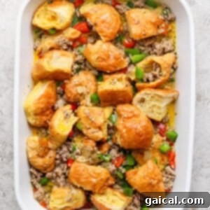 Buttery Croissant Egg Bake 9 A baking dish filled with a savory casserole base of browned bread pieces, cooked ground meat, and vibrant chopped green and red peppers, tossed together.