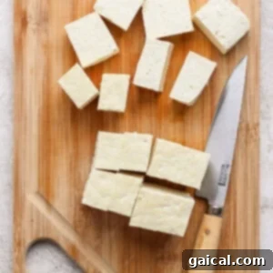 Cubed tofu on a wooden cutting board with a knife.