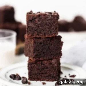 Decadent Chocolate Brownie Protein Creami Ice Cream 5 A perfectly stacked tower of homemade chocolate brownies on a pristine white plate, promising rich, fudgy goodness.
