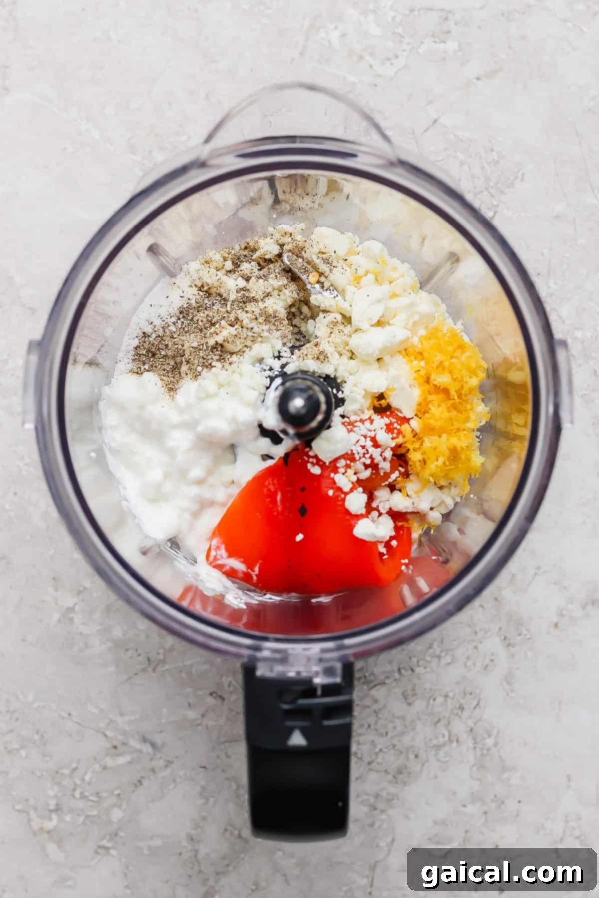 Creamy Roasted Red Pepper Pasta Delight 3 Ingredients including pepper, feta cheese, cottage cheese, lemon zest, and red peppers in a food processor, ready to be blended.