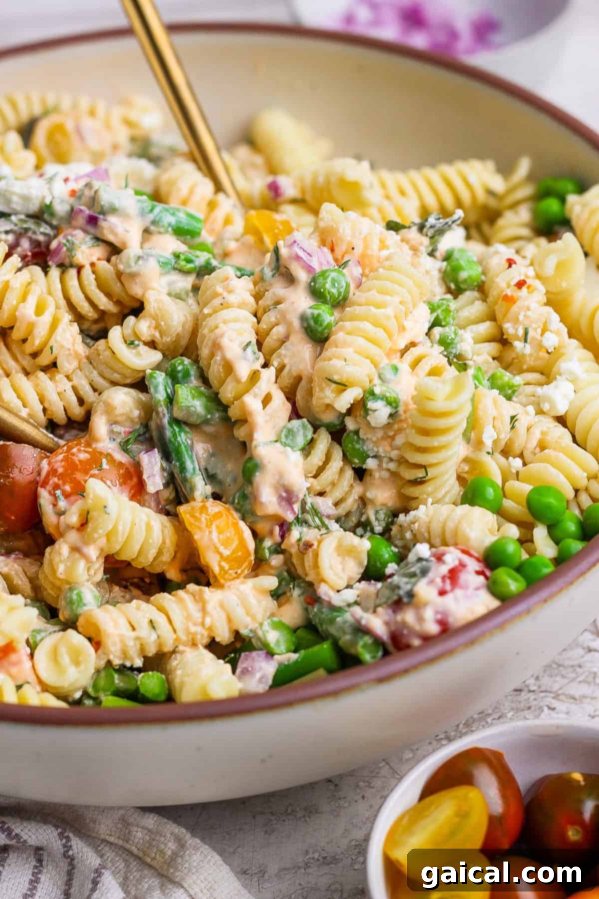 Creamy Roasted Red Pepper Pasta Delight 6 A bowl of rotini pasta salad with peas, asparagus, cherry tomatoes, and a creamy dressing.