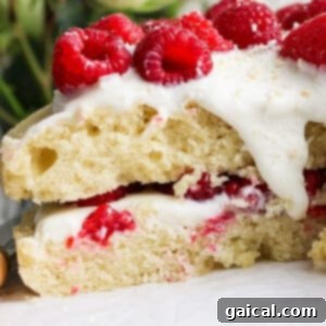 Layered Coconut Bliss with Fresh Raspberries 11 A close-up of a beautifully garnished coconut layer cake, showing its layers of white frosting and fresh raspberries, with white roses softly blurred in the background.