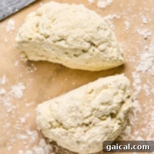 Two pieces of dough sit on a floured surface next to a knife, ready to be transformed into homemade pizza pockets.