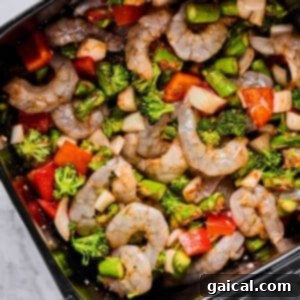 Crispy Air Fryer Shrimp and Roasted Vegetables 6 Raw shrimp, chopped broccoli, asparagus, red bell peppers, and onions arranged in an air fryer basket, ready to be cooked.