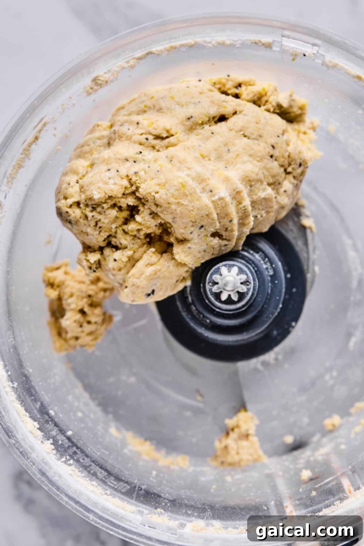 Protein-Packed Cottage Cheese Fruit Pizza 4 A close-up view of freshly mixed dough, smooth and cohesive, forming a soft ball within the base of a food processor bowl, with the metal blade visible above it.
