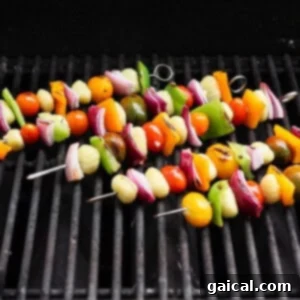 Vibrant Grilled Gnocchi Kebabs 10 Vegetable skewers with tomatoes, onions, bell peppers, and gnocchi are grilling on a barbecue grate.