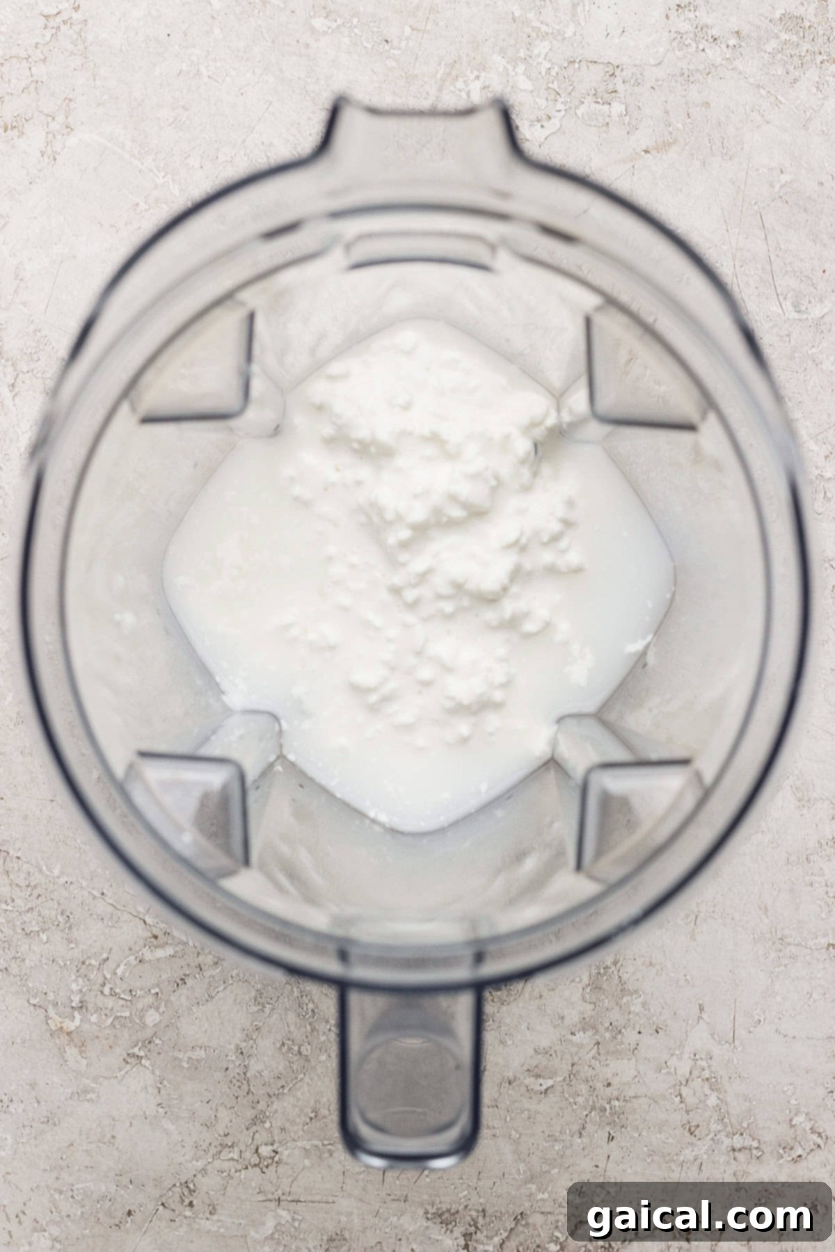 A clear blender jug filled with a foamy, light-colored liquid, indicating a smooth and well-blended batter, viewed from a top-down perspective.