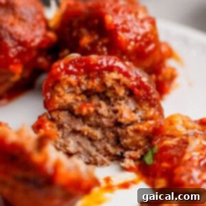 A close-up of a partially eaten sloppy joe meatball covered in rich tomato sauce, showcasing its perfectly cooked, tender interior.