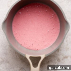 Gourmet Strawberry Toaster Tarts 9 A beige saucepan filled with a pink liquid mixture sits on a light textured surface, viewed from above.