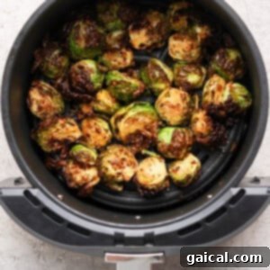 Halved Brussels sprouts cooked in an air fryer basket, showing a browned, crispy texture on a light gray countertop.