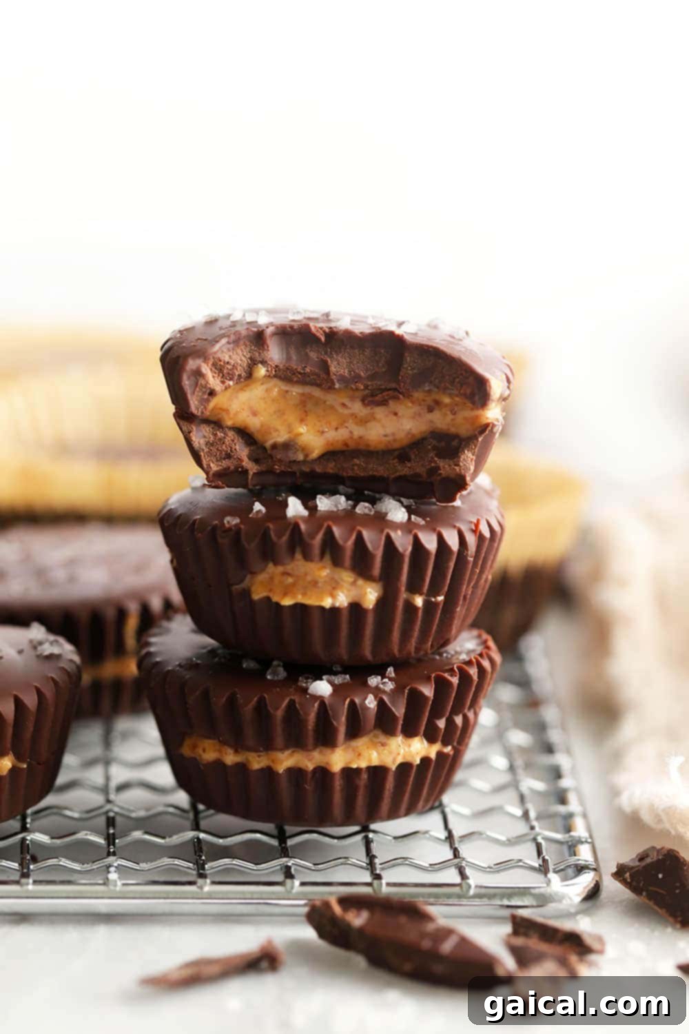 Stacked homemade almond butter cups, showcasing their irresistible layers of chocolate and creamy filling topped with sea salt.