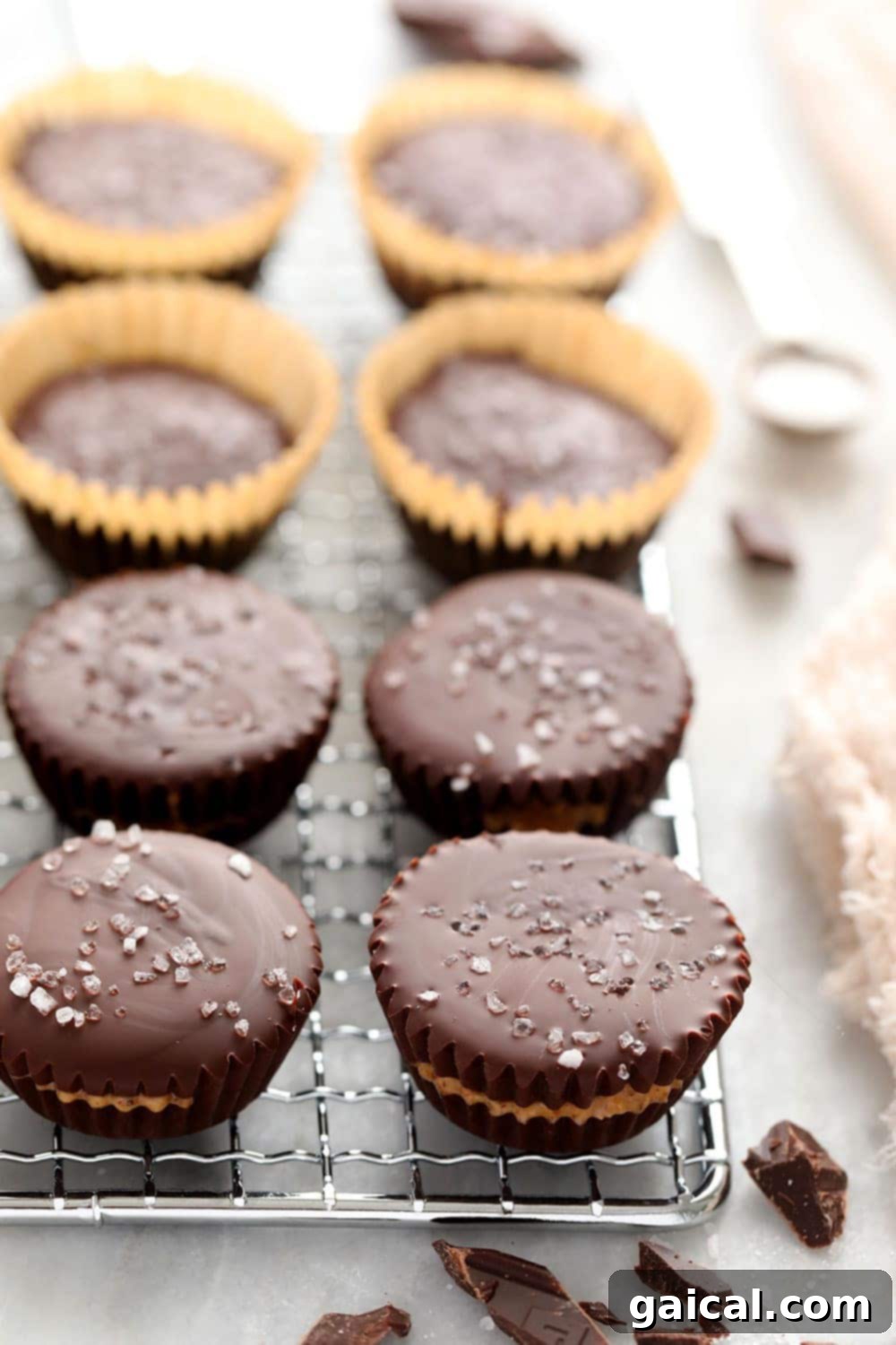 Homemade almond butter cups cooling on a metal rack, showcasing their perfect shape and flaky sea salt topping.
