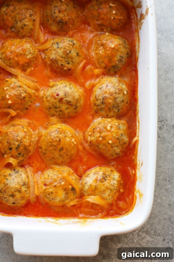 Close-up of flavorful curry meatballs generously coated in vibrant red curry sauce