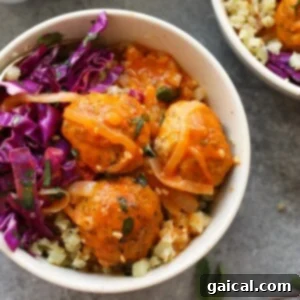 Two bowls with red curry meatballs and cabbage salad, showcasing the complete meal