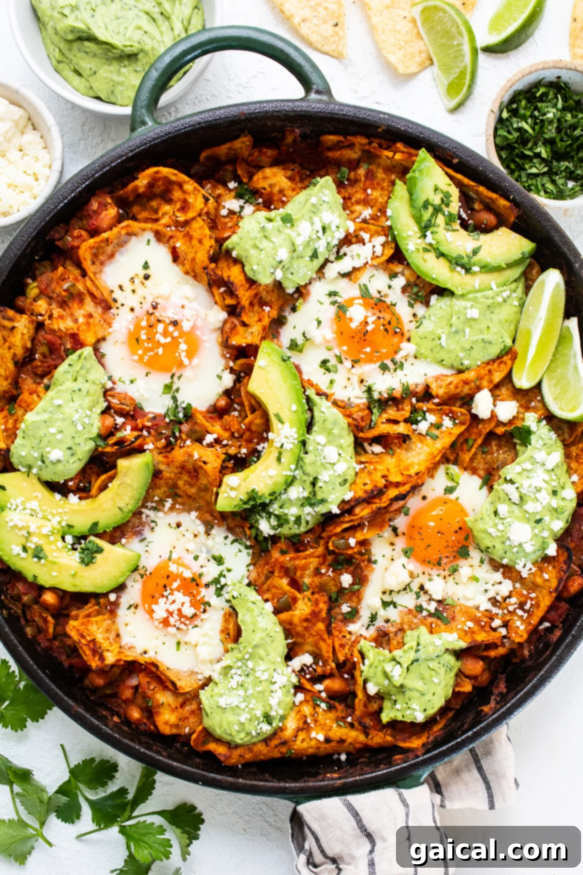 Delicious chilaquiles with a generous dollop of avocado crema and fresh cilantro, served fresh in a cast iron skillet, ready to be enjoyed.