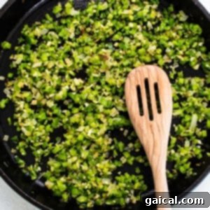 Green onions and bell pepper sautéing in a cast iron skillet, forming the aromatic base for the chilaquiles sauce.