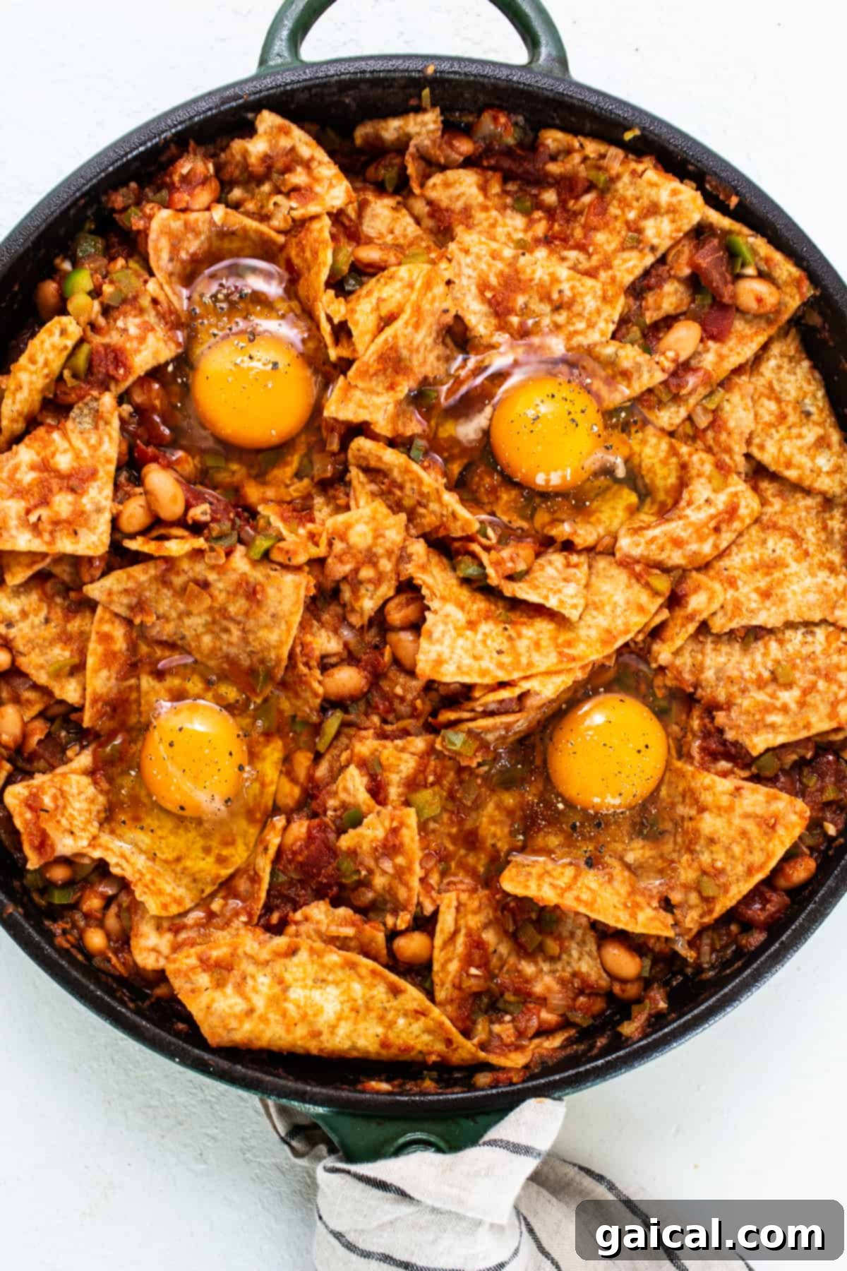 Chilaquiles garnished with perfectly baked eggs, a sprinkle of fresh cilantro, and ready for the final touch of avocado crema, creating a satisfying and protein-rich meal.