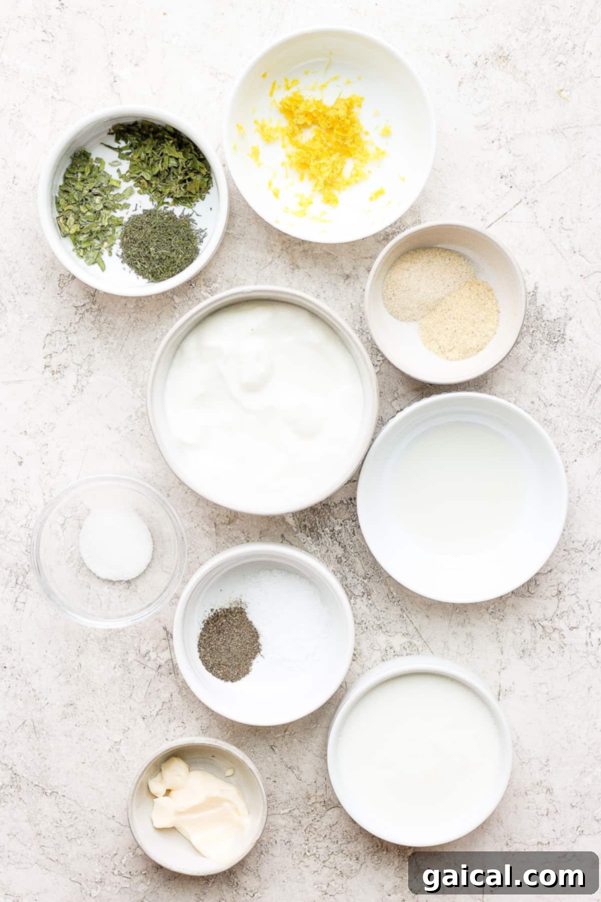 Ingredients for homemade ranch dressing displayed on a kitchen counter. An array of fresh ingredients for homemade ranch dressing laid out on a countertop.