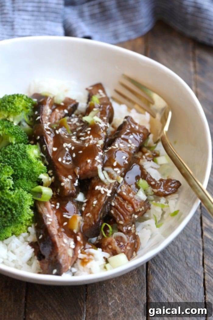 Achieve the most tender Mongolian Sous Vide Flank Steak with this easy recipe! Sous vide flank steak on rice with garnishes, showcasing its tender texture.