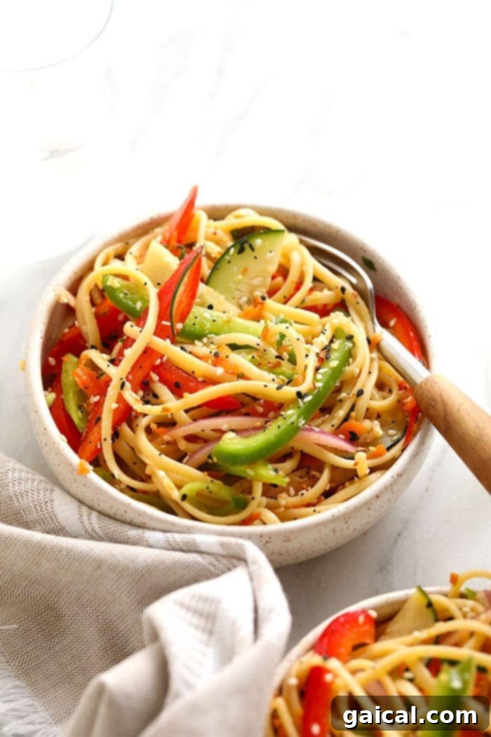 A beautifully presented Asian noodle salad in a large bowl, showcasing a medley of colorful vegetables and noodles tossed in a rich dressing.
