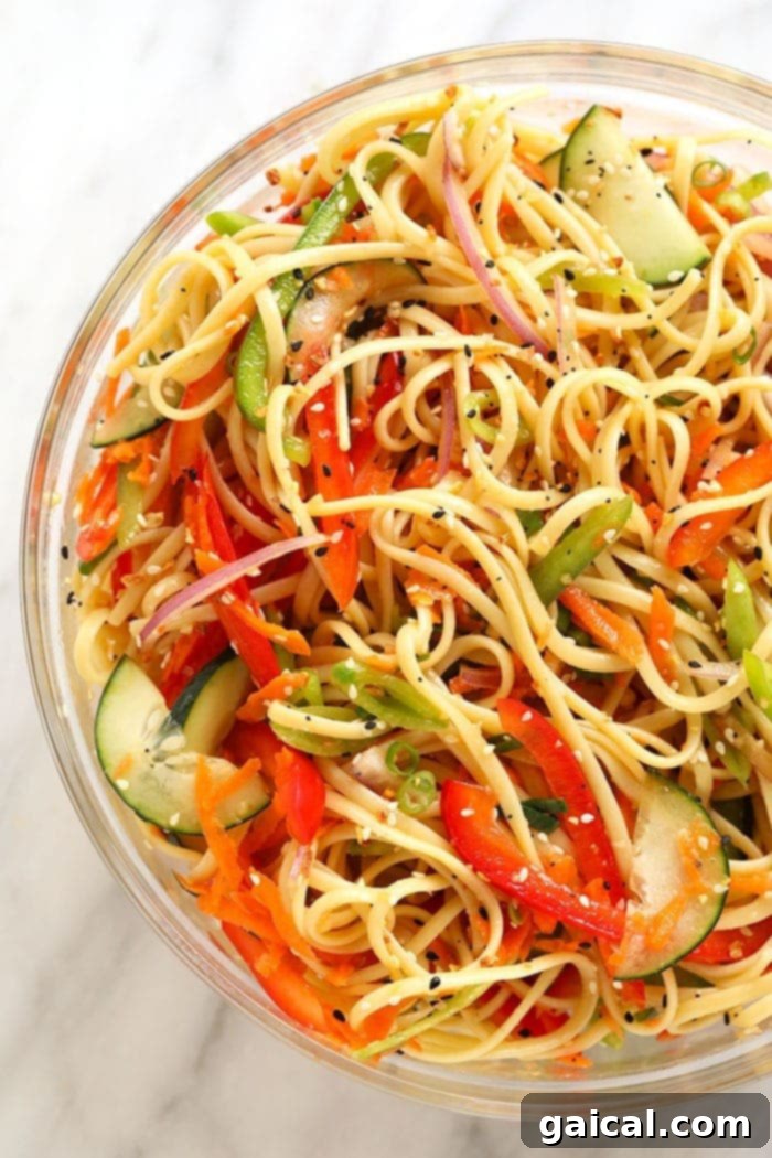 A large serving bowl filled with a vibrant cold Asian noodle salad, ready to be enjoyed. The colorful vegetables and rich dressing are clearly visible.