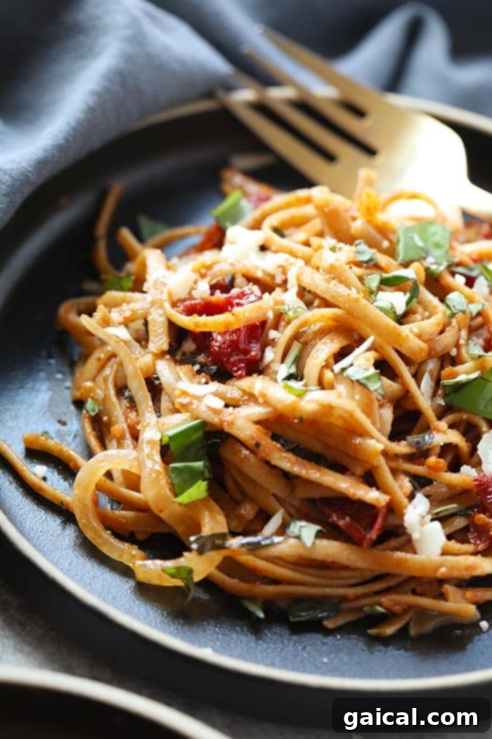 A plate of healthy Whole Wheat Sun Dried Tomato Basil Pasta, garnished with fresh basil leaves, showcasing the rich colors of the sauce and the texture of the whole wheat noodles.
