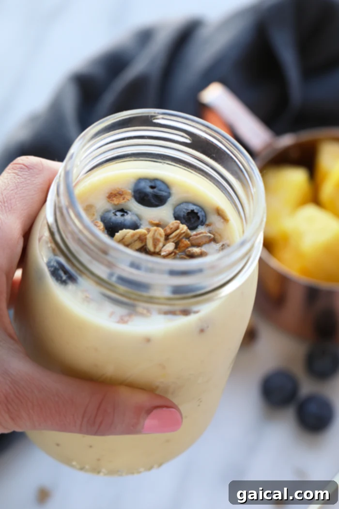 Zesty Pineapple Ginger Quencher 4 Overhead shot of a delicious ginger pineapple smoothie next to a healthy breakfast bowl with granola and blueberries, highlighting a perfect start to the day.