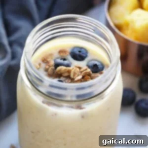 Breakfast in a jar with blueberries and granola, accompanied by a ginger pineapple smoothie, representing a complete healthy meal.