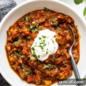 Harvest Pumpkin Chili 3 A perfectly portioned bowl of turkey pumpkin chili, garnished with a dollop of sour cream and fresh herbs, ready for immediate enjoyment.