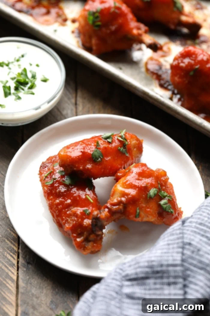 Crispy Baked Buffalo Chicken Wings for Game Day Three perfectly crispy baked buffalo chicken wings served on a clean white plate, glistening with a sweet and spicy sauce, ready to be enjoyed.