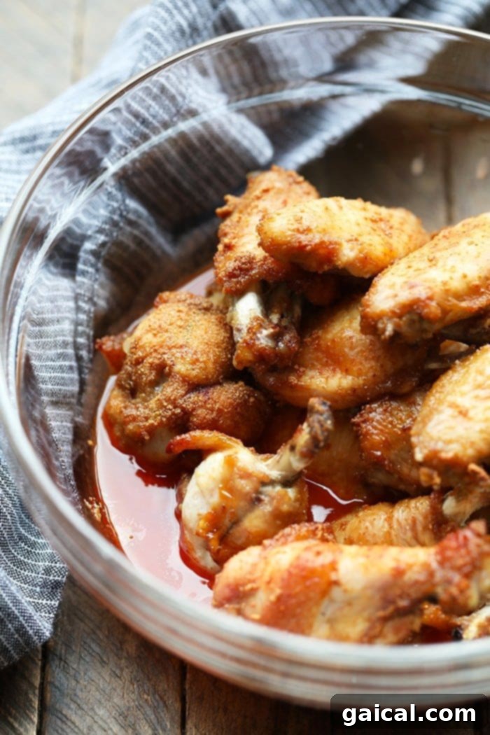 Chicken Wings Marinating in Buffalo Sauce Raw chicken wings are shown marinating in a glass bowl with a rich, vibrant sauce, ensuring every piece is thoroughly coated before baking.