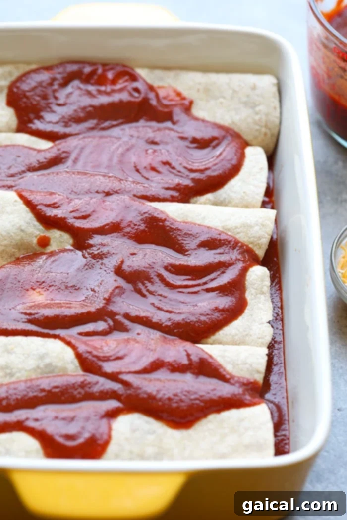 Homemade Enchilada Sauce on Chicken Enchiladas Healthy enchiladas covered in rich red homemade enchilada sauce in a baking dish, ready for the oven.