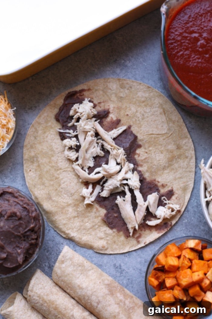 Assembling Healthy Chicken and Black Bean Enchiladas Close-up of shredded chicken and black beans being added to an open tortilla, ready for rolling.