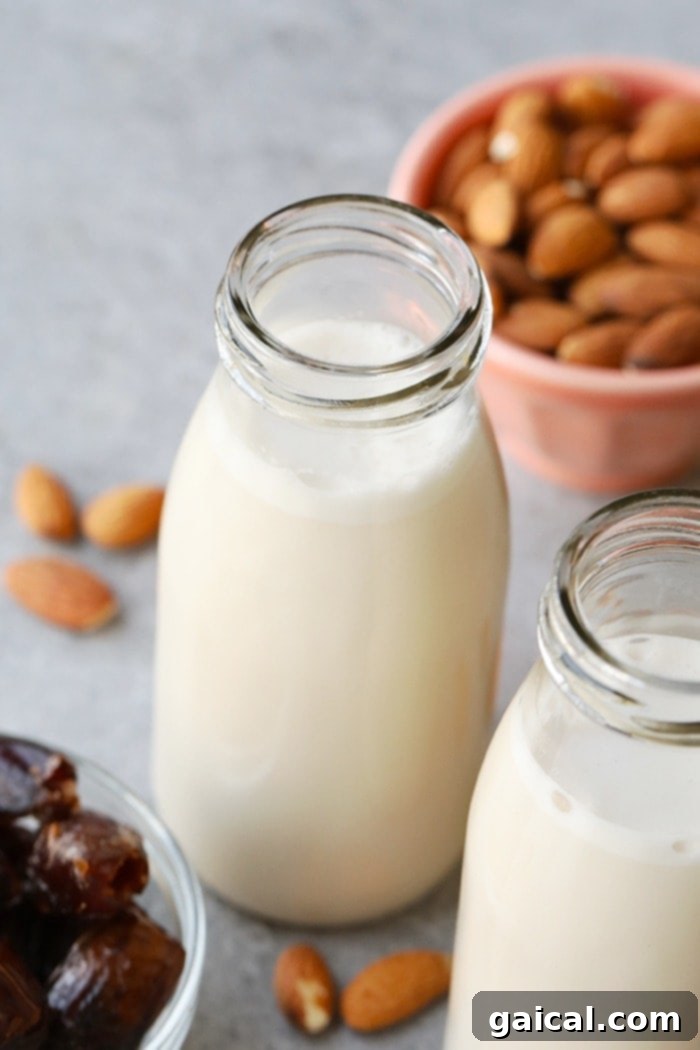 A beautiful glass jug filled with freshly prepared homemade date-sweetened almond milk, elegantly garnished with a whole vanilla bean, positioned on a wooden surface ready for serving.