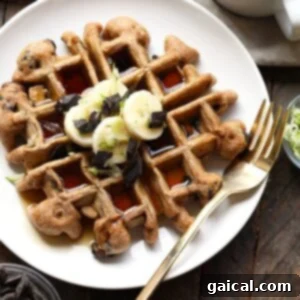 Chocolate chip and banana waffles, garnished with zucchini, on a light plate.