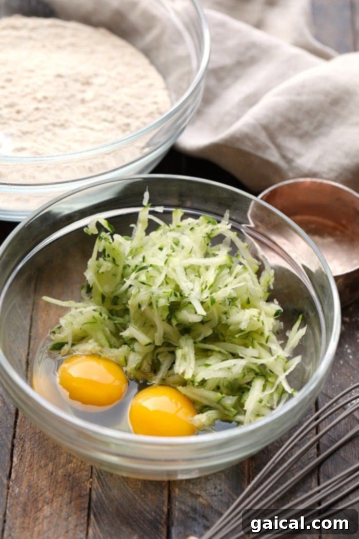The foundation of our zucchini waffles: fresh shredded zucchini and large eggs, ready for mixing into a wholesome batter. Freshly shredded zucchini alongside raw eggs, essential ingredients for making healthy and flavorful zucchini waffles.