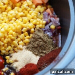A slow cooker filled with ingredients for Mexican quinoa before cooking.
