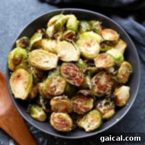 Roasted brussels sprouts with parmesan, served in a black bowl.