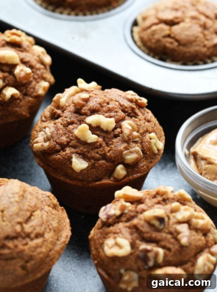 Nutritious Pumpkin Spice Muffins 2 Healthy pumpkin muffins arranged beautifully on a countertop, showcasing their golden tops and moist interior. Some muffins feature crunchy walnut toppings.
